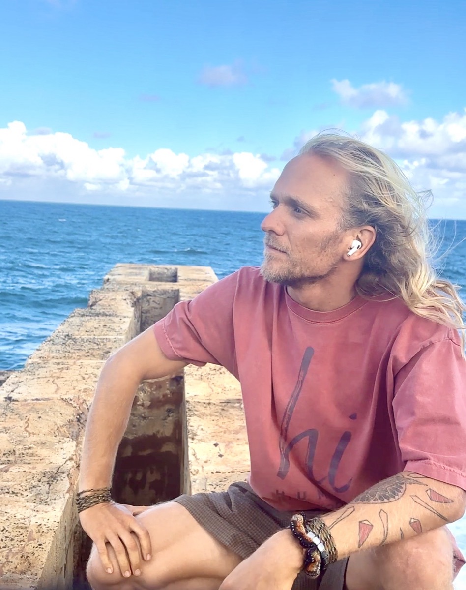 Alex wearing the HI Classic Tee and HI Cap at an ocean overlook, Kauai, HI